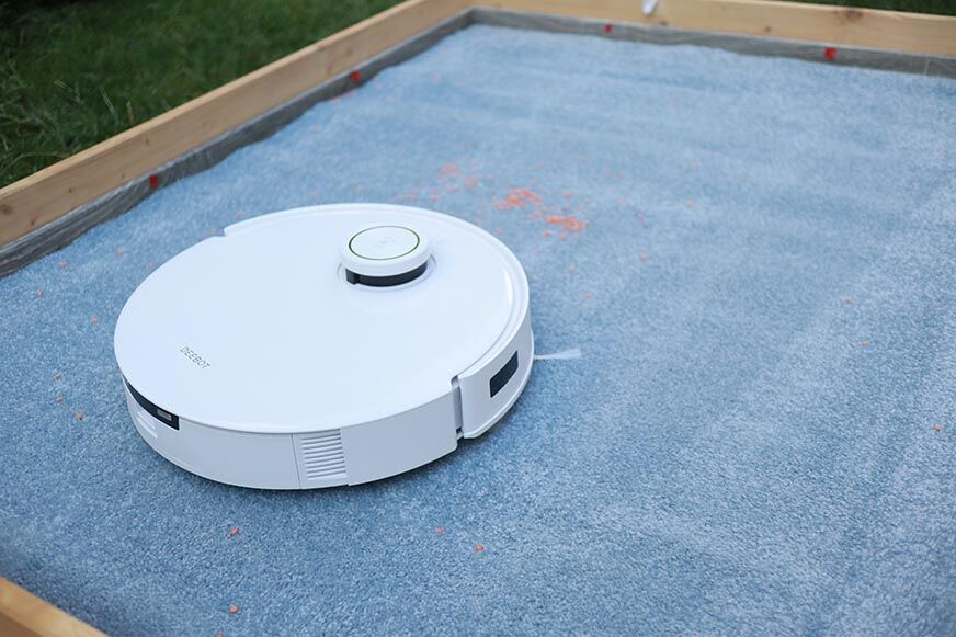 Ecovacs Deebot T10 reinigt im Test Linsen auf einem hohen Teppich.